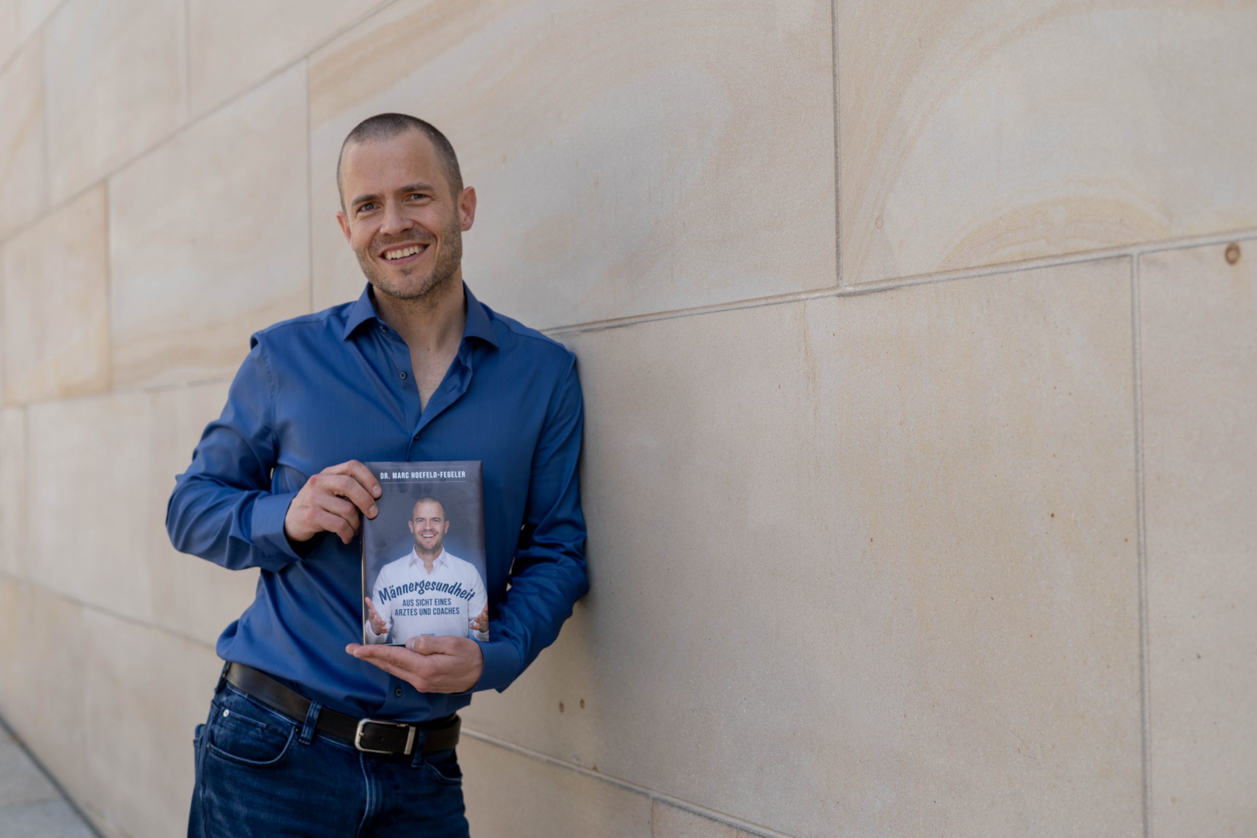 Dr. Marc steht mit seinem Buch "Männergesundheit" in der Hand, vor der NRW Bank in Münster